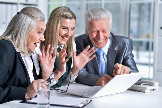 Three mature business people using laptop