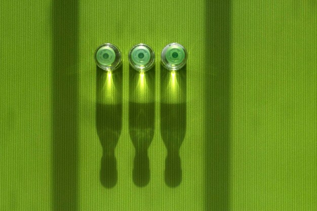 three medicine ampoules with injection are standing on the green table with top view