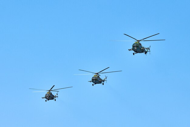 Photo three military helicopters flying in bright blue sky while performing demonstration flight, copy space. aerobatic team performs flight at air show