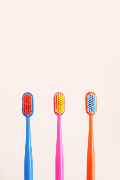 Three multicolored toothbrushes on a beige background copy spacexA