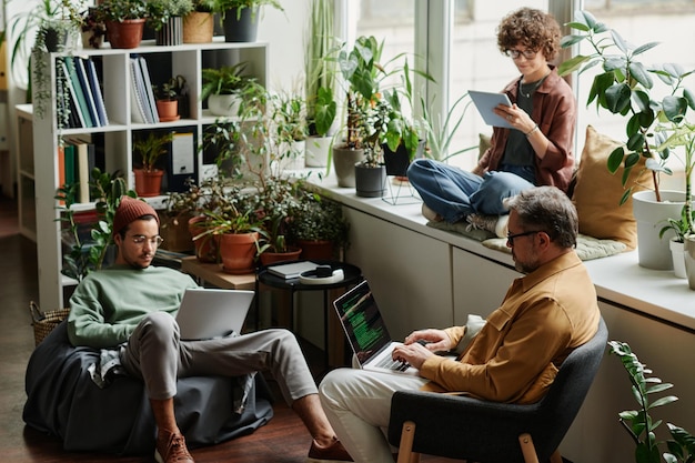 Three multicultural coworkers in casualwear using mobile gadgets