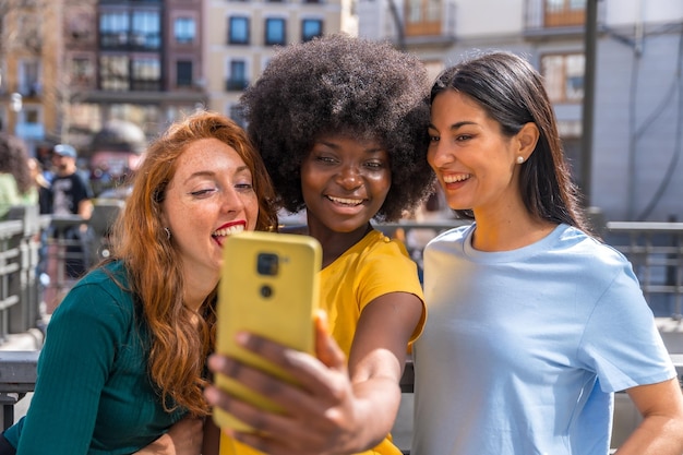 Three multiracial young women taking a selfie in the city friendship concept feminism