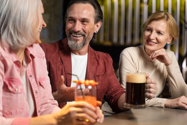 Three older friends drinking and talking at a restaurant