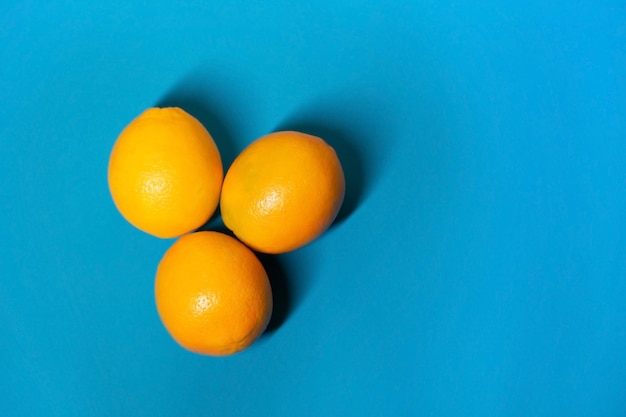 Three oranges lie on a blue background