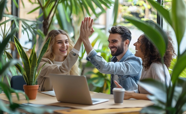 Three people are highfiving each other in front of a laptop Scene is happy and celebratory