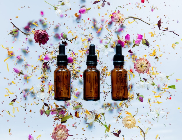 Three Perfume bottle and dry flowers around on white surface