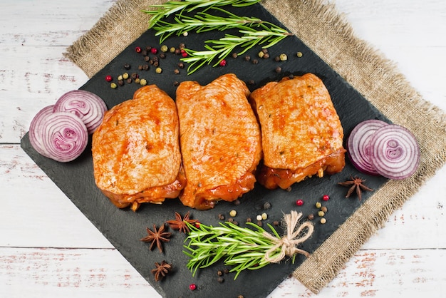 Three pieces of chicken thighs marinated in red sauce on a kitchen cutting board light background