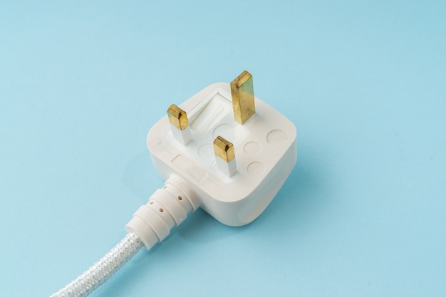 Three pin plug on light blue background with a copy space.