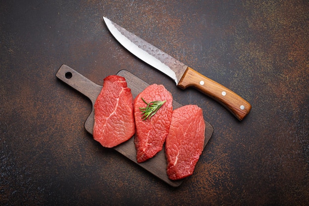 Three raw uncooked meat beef top sirloin steaks on wooden