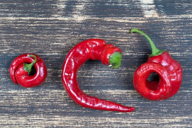 Three red bell peppers on old wooden background close up top view