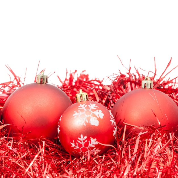 Three red Christmas baubles and tinsel isolated