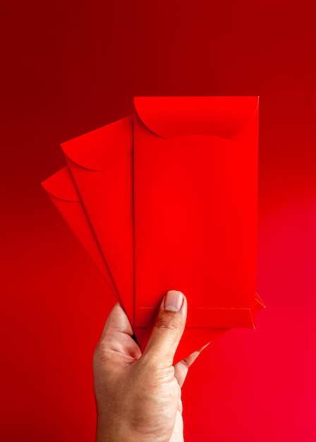 Three red envelope holding by hand isolated on red background vertical style 3 Hongbao packets for lucky money gift in Chinese lunar new year on January month wedding red packet