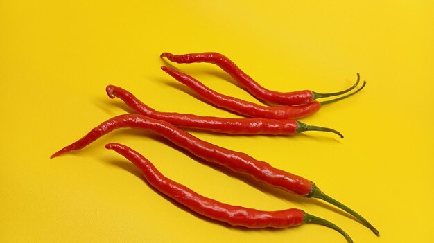 three red peppers are laying on a yellow surface