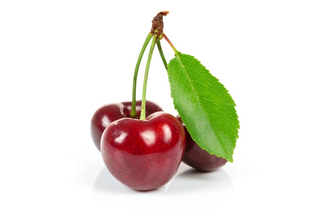 Three ripe cherries with leaf isolated on a white background in closeup