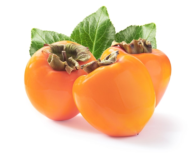 Three ripe juicy persimmons with a green leaves isolated on white background