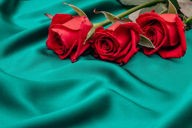 Three  roses lying on a green silk