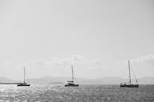 Three sail boat in the sea near Aegina island, Greece. Black and white photography, seascape