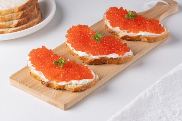 Three sandwiches with red caviar on a cutting board A delicious appetizer of trout caviar