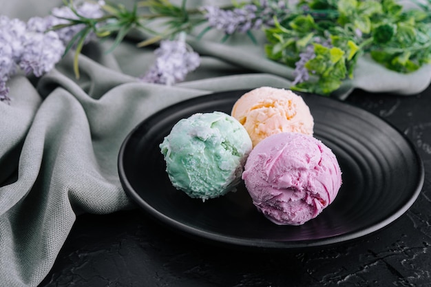 Three scoops of ice cream on dark plate