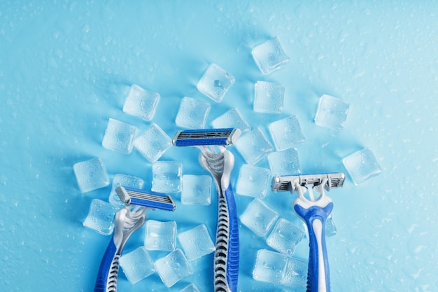 Three shaving machines on a frosty blue background with ice The concept of cleanliness and frosty freshness