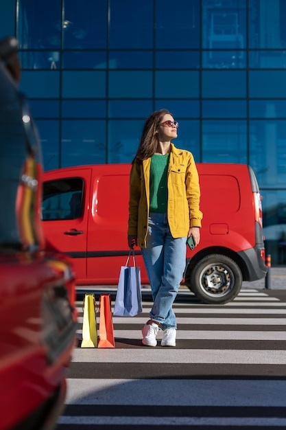 Three shopping paper bags and woman standing on marked crosswalk