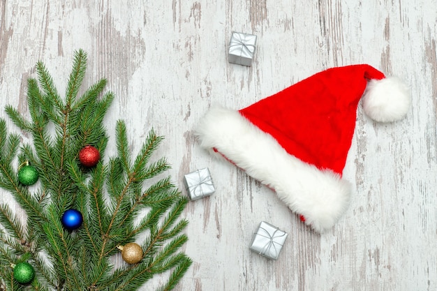 Three silvery gift boxes, decorated with a Christmas tree and a Santa hat. Wooden background