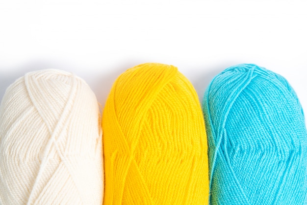 three skeins of woolen threads on a white background, white, yellow and blue