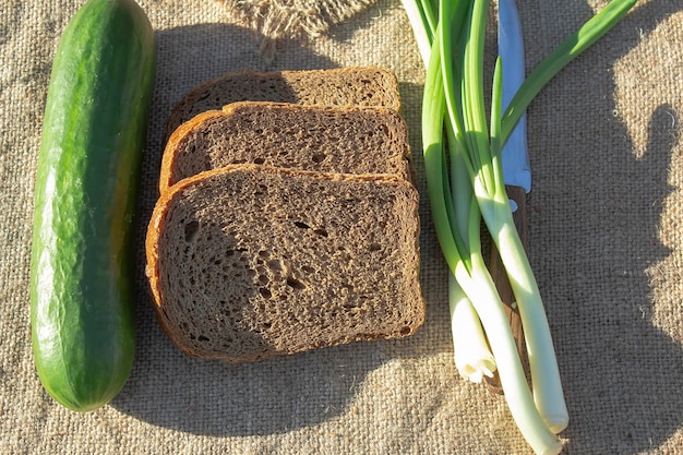 Three slices of bread a cucumber and an onion feather lie on a linen tablecloth on a table