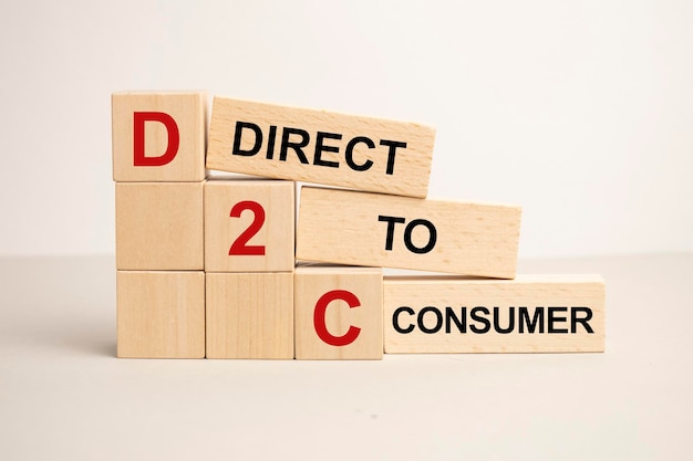 Three stone cubes on the background of white financial statements tables with the word D2C acronim Direct to Consumer Strong business concept Gray background