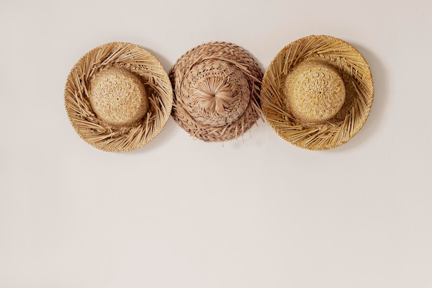 Three straw hats on a beige wall with copy space