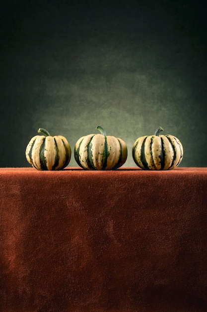 Three striped decorative pumpkins on a brown table