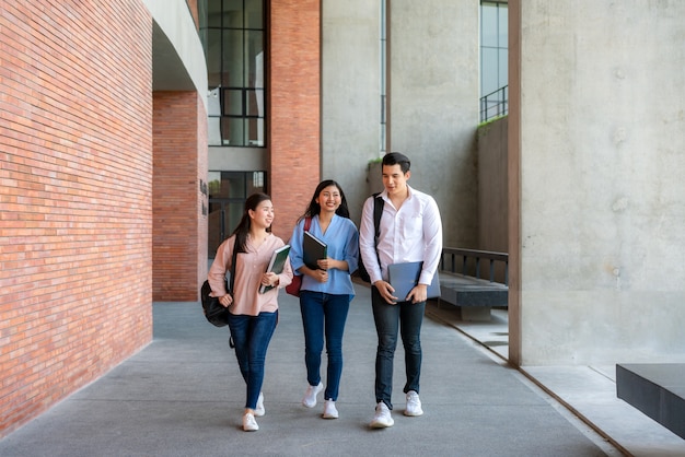 three students are walking and talking together in university hall