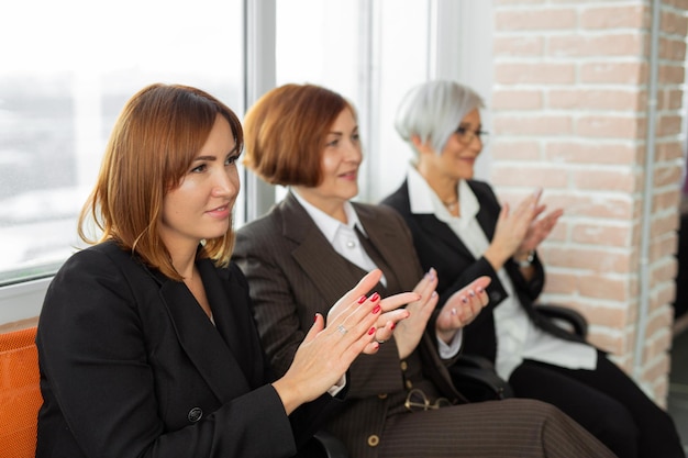 three successful business women clapping their hands