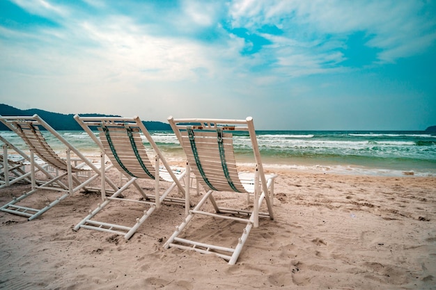 Three sun loungers stand on the white sand against the blue sky and the clear sea with turquoise water concept of recreation at the resort