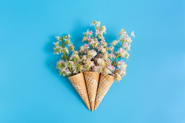 Three sweet crispy wafer cups with chestnut flowers on a blue background