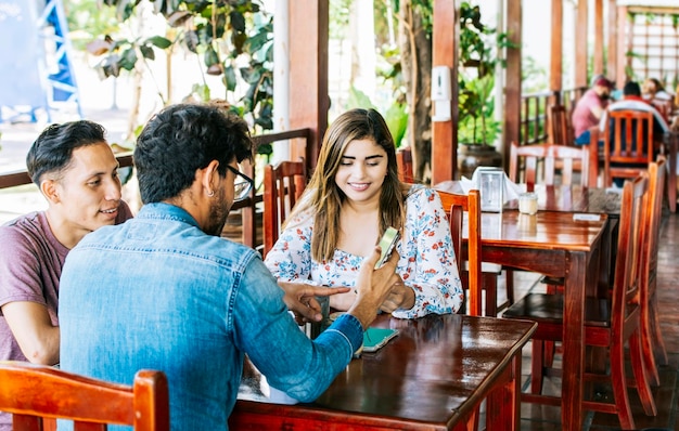 Three teenage friends on their cell phones in a coffee shop Young friends in a coffee shop with their cell phones having a good time Three people in a coffee shop with phones having a good time