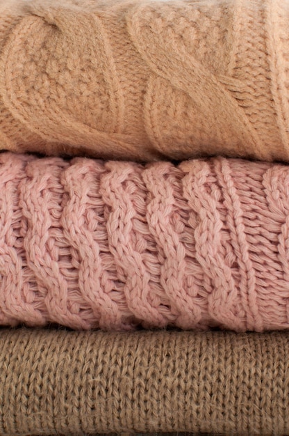 Three textures of knitted sweaters in beige and pink colors in vertical format