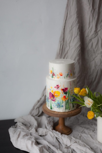 A three - tiered cake with a painted flower on the top.