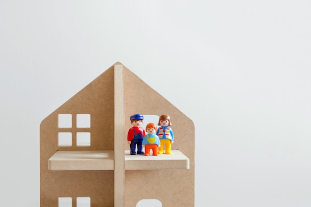 Three toy figures of men-a man, a woman and a child in a wooden toy house.