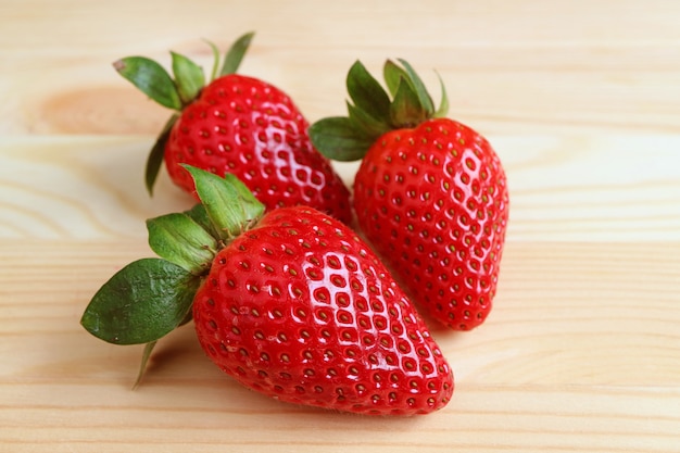 Three of Vibrant Red Fresh Ripe Strawberry Fruits on Wooden Table