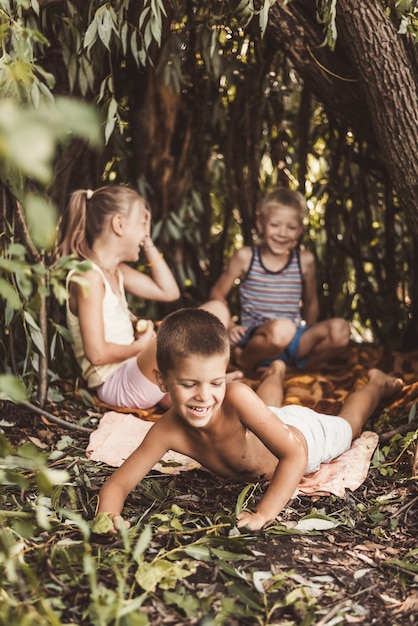 Three village children are playing in a hut which they themselves have built from leaves and twigs