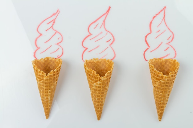 Three waffle cones with hand drawn cream on white surface top view flat lay