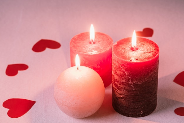 Three wax flame candlelight with paper red hearts valentines on white