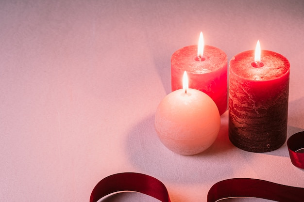 Three wax flame candlelight with red ribbon on white