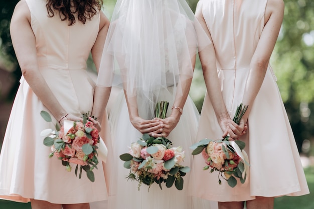 Three wedding bouquets being held by a bride and her bridesmaids