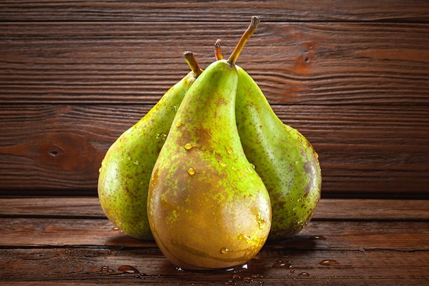 Three wet pears with drops of water on a dark wooden background