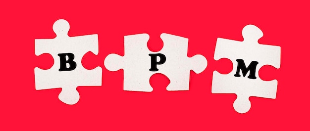 Three white jigsaw puzzles with the text BPM Business Process Management on a bright red background