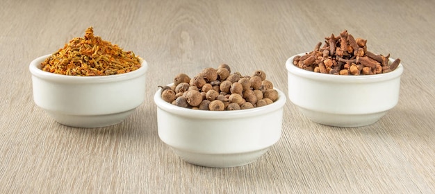 Three white saucers with various seasonings of a bright color are arranged in a triangle on a wooden table