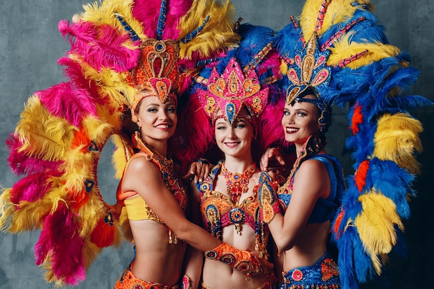 Three women dancers in brazilian samba carnival costume with colorful feathers plumage