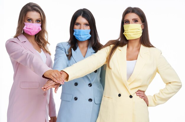 three women in pastel suits posing over white background